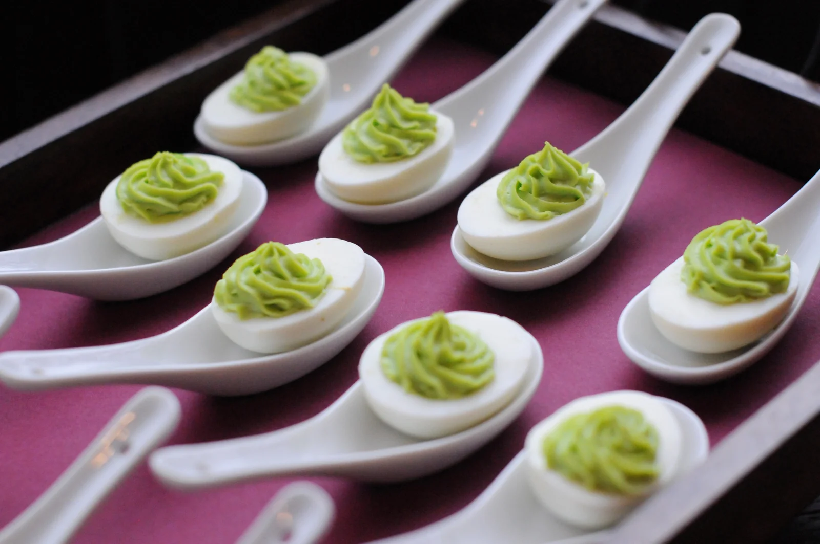 Deviled eggs piped with herbed filling, served on porcelain spoons