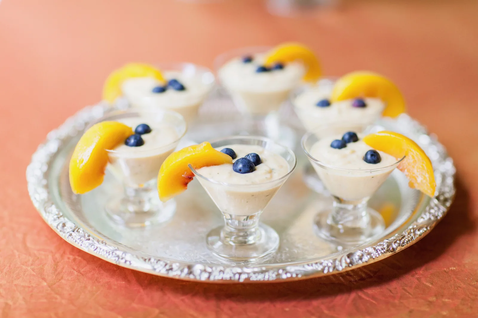 Lemon possets topped with blueberries and lemon, arranged on a silver tray