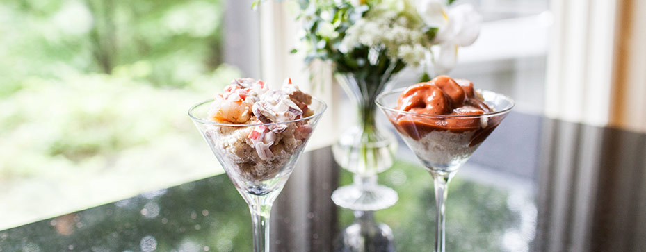Two servings of shrimp and grits presented in stemmed glasses on a table